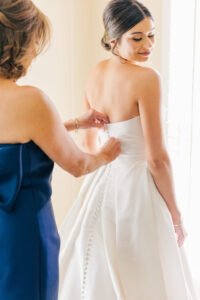 bride getting dressed with mother buttoning gown during bridal getting ready photos in Atlanta wedding