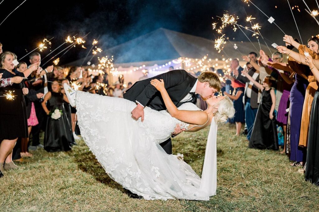 Bride and groom sharing dramatic dip kiss during sparkler exit at private estate wedding in Lake Mary