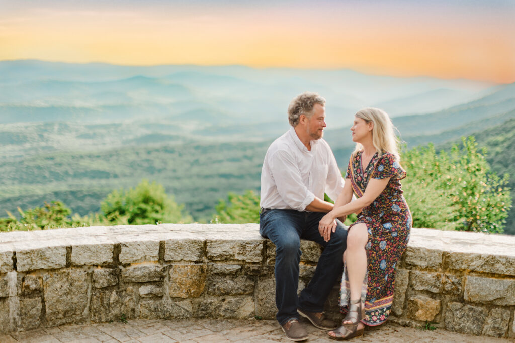 Romantic Amicalola Falls engagement photos of a couple seated together at sunset overlooking the North Georgia mountains