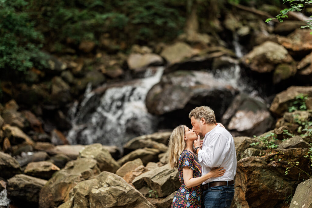 Couple embracing beside a waterfall during Amicalola Falls engagement photos in the North Georgia mountains