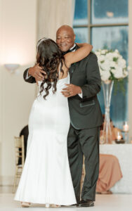 Emotional wedding photo of a bride sharing a heartfelt hug with her father during the celebration