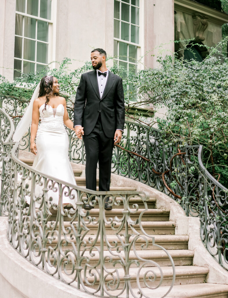 Editorial documentary wedding portrait of bride and groom walking down the iconic Swan House staircase in Atlanta