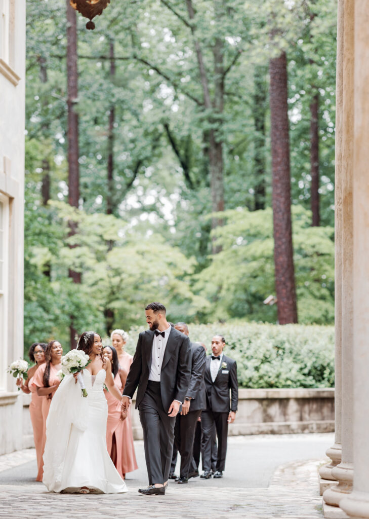 Storytelling wedding photography of bride and groom walking with wedding party at Swan House 