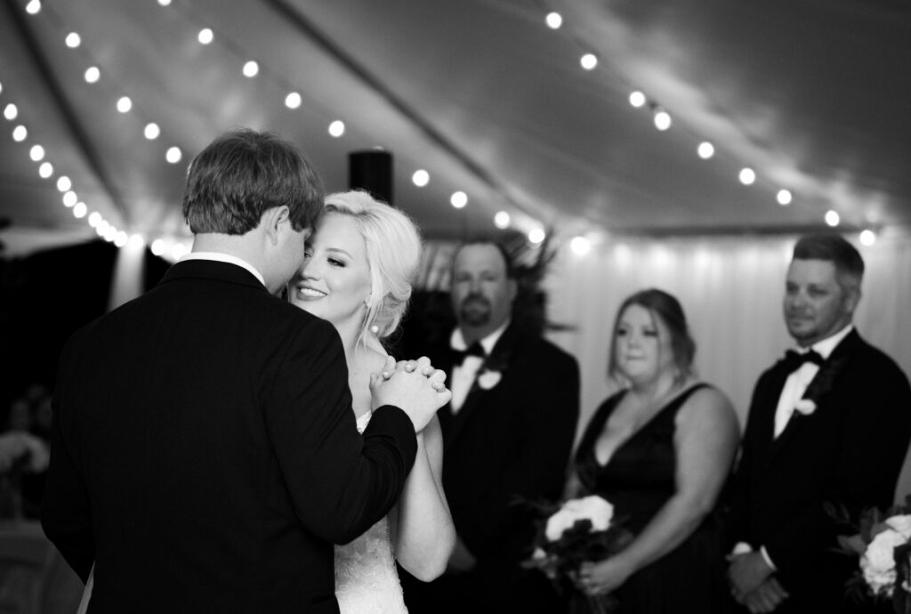 Bride smiling during first dance with groom at private estate wedding reception under string lights