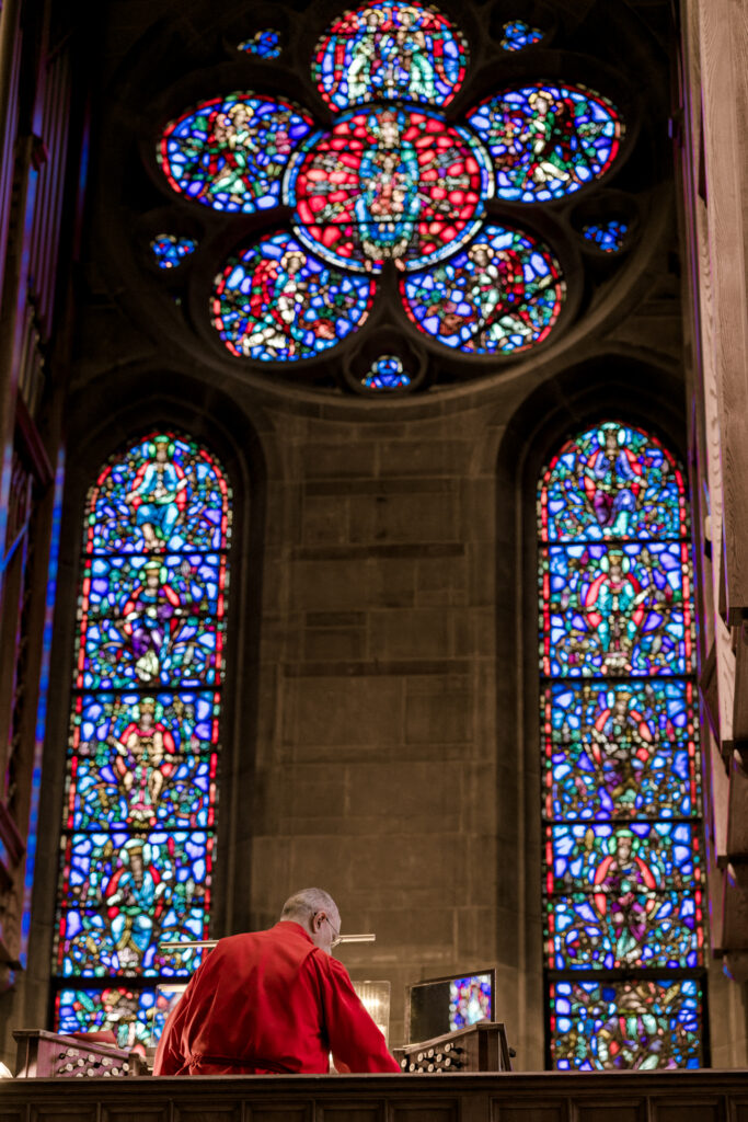 Cathedral of Christ the King wedding Atlanta Georgia, organist in front of stain glass windows. 
