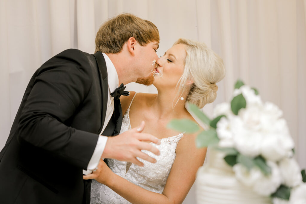 Bride and groom kissing during wedding cake cutting at private estate wedding reception in Lake Mary