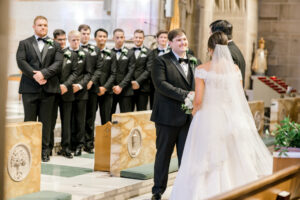 Groom watching bride walk down the aisle at Christ the King Cathedral wedding in Atlanta Georgia