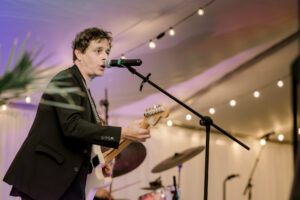 Live musician performing during private estate wedding reception under reception tent lights