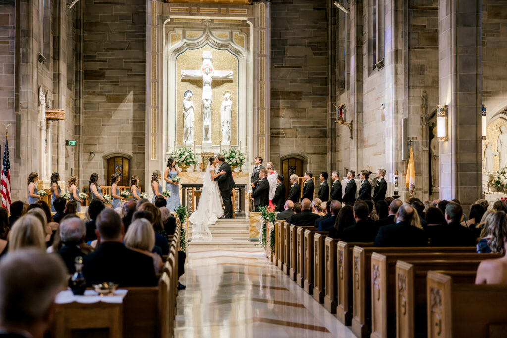 Wide angle ceremony photograph inside Christ the King Cathedral during elegant Atlanta wedding first kiss