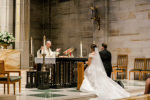 Wide ceremony photograph inside Christ the King Cathedral during elegant Atlanta wedding ceremony as couple prepares to receive communion. 