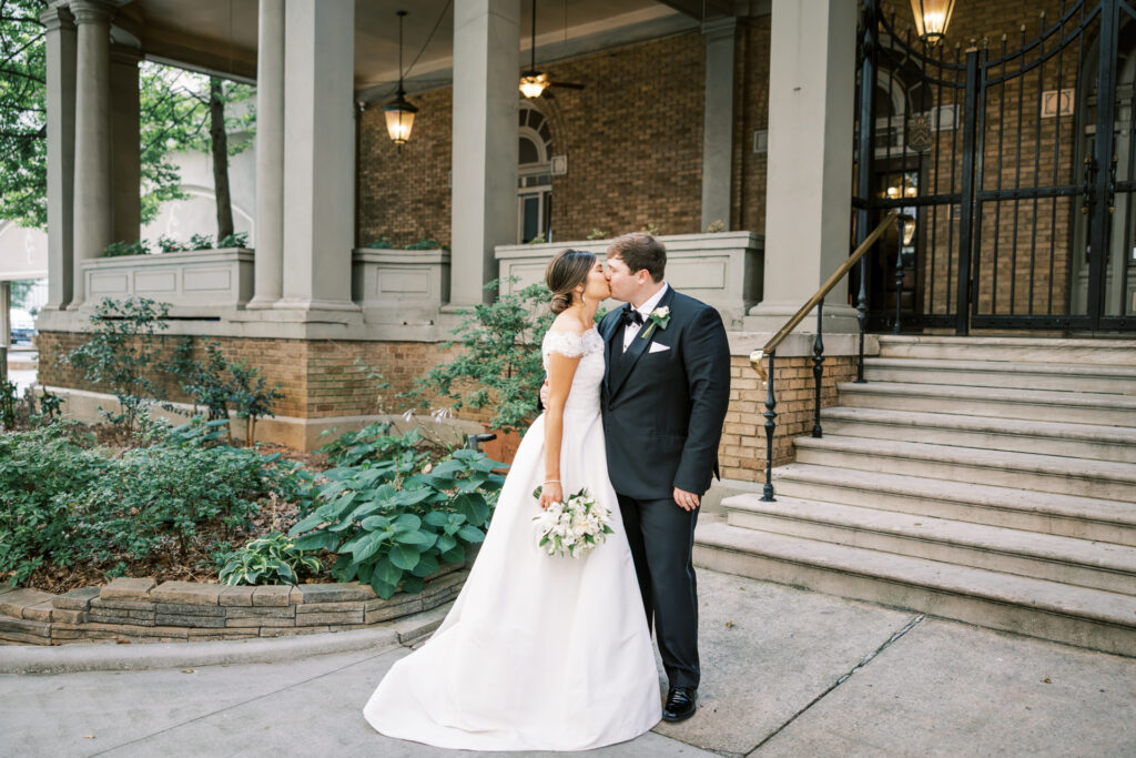 Romantic bride and groom kiss outside Capital City Club wedding venue in Atlanta Georgia
