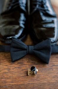 Elegant groom wedding accessories including tuxedo shoes bow tie and ring photographed for a private estate wedding