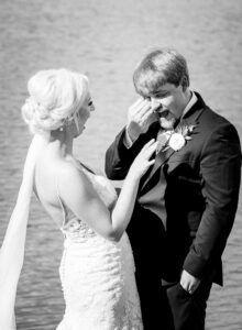 Black and white portrait of bride and groom sharing an emotional first look beside the lake during a private estate wedding