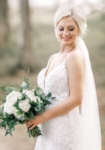 Bride smiling softly while holding bouquet during editorial bridal portraits at a private Lake Mary wedding