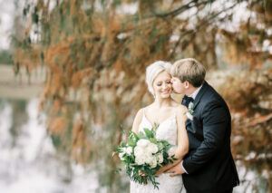 Groom kissing bride on the cheek during romantic outdoor portraits at a private Lake Mary wedding
