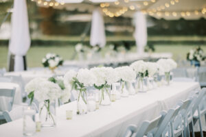 Elegant outdoor reception table with white floral arrangements and string lights at a private Lake Mary wedding