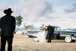 Bride arriving with family beside a vintage car during a private estate wedding at Lake Mary