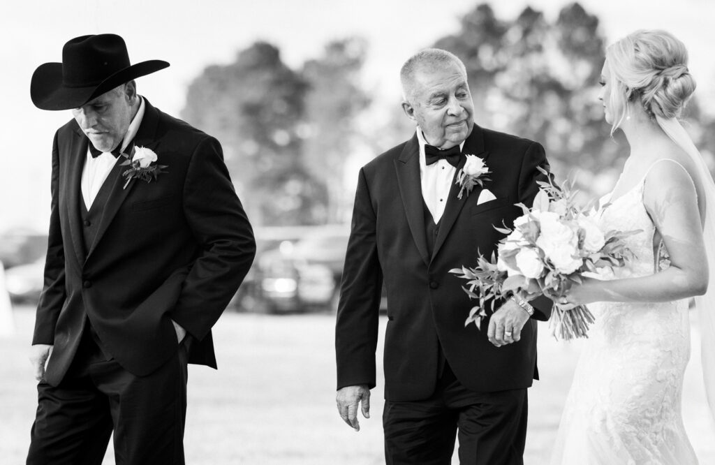 Black and white portrait of bride walking with her father before an outdoor private estate wedding ceremony