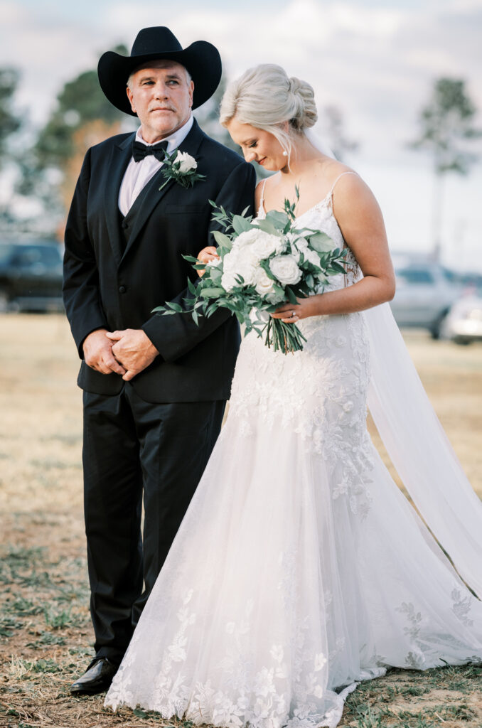 Bride looking down while standing beside her father before a private estate wedding ceremony at Lake Mary