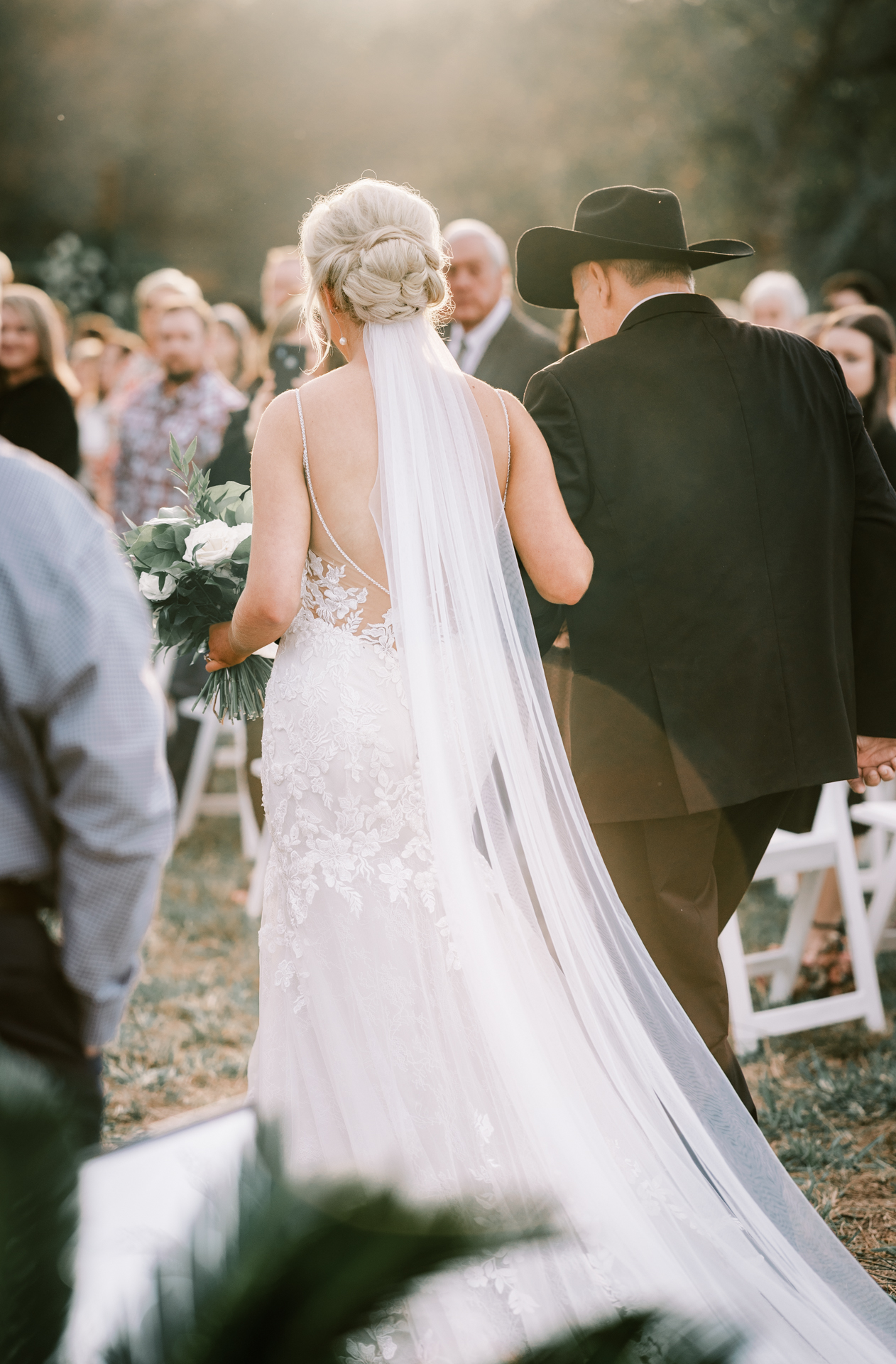 Bride walking down the aisle with her father during a sunset private estate wedding ceremony at Lake Mary