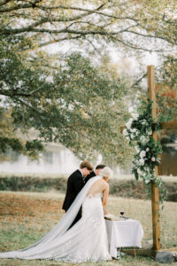 Bride and groom standing together beneath floral cross during a private Lake Mary wedding