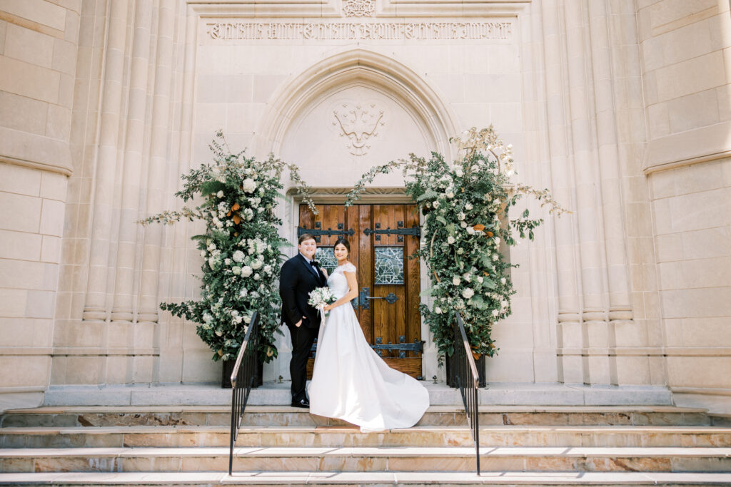 Editorial bride and groom portrait in front of Christ the King Cathedral doors with floral installations