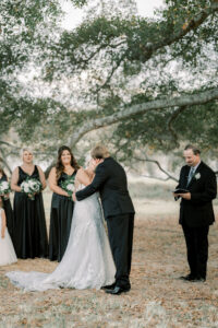 bride and groom share their first kiss beneath the oak tree at lake mary