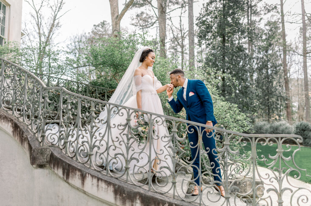 Luxury documentary Atlanta wedding photographer capturing groom kissing the bride’s hand on the iconic curved staircase at Swan House in Atlanta