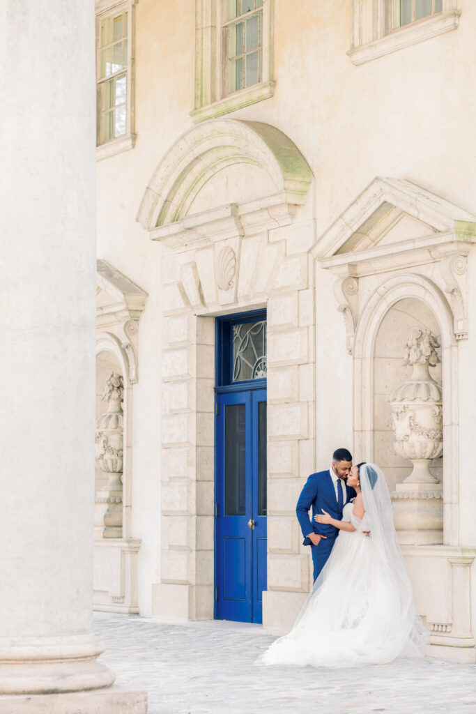 Timeless Swan House wedding portrait of bride and groom looking lovingly at each other beside iconic blue doors by a luxury documentary Atlanta wedding photographer