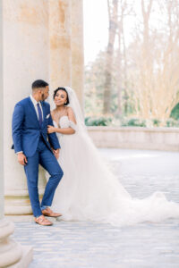 Bride and groom smiling together beneath the grand columns at Swan House captured by a luxury documentary Atlanta wedding photographer in Atlanta