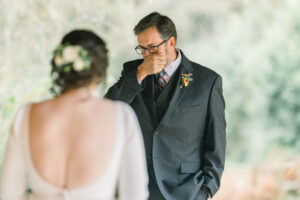 Emotional wedding photo of a groom seeing his bride during a heartfelt first look moment