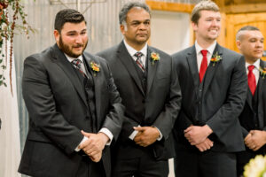 Emotional wedding photo of a groom reacting during the ceremony surrounded by family and friends